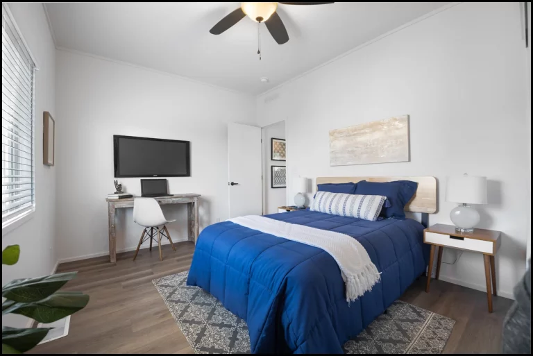 a bedroom with a blue bed and a desk
