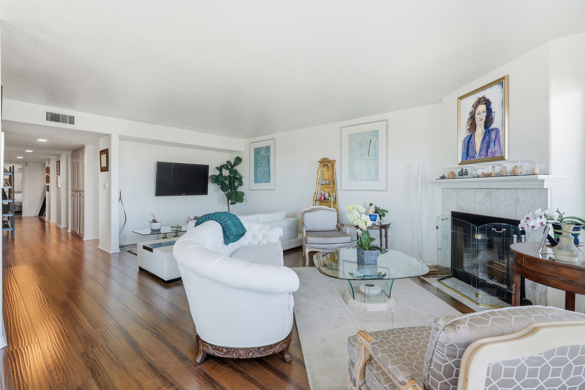 Open-concept living area with white seating, fireplace, and hardwood floors