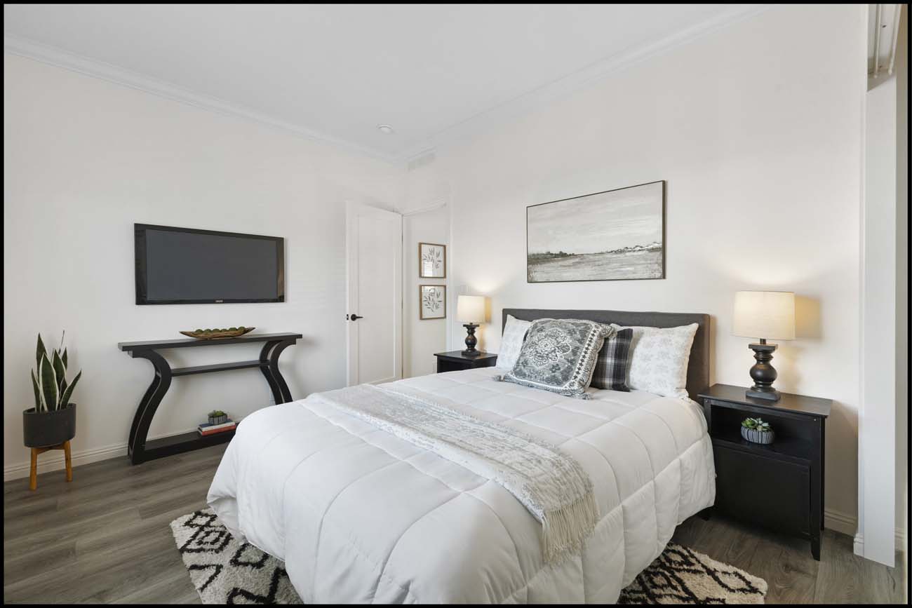 Normandie Avenue bedroom with wall-mounted television and white bedding